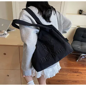 Dettaglio della borsa tote nera con ricamo Chase My Dreams e trama in nylon