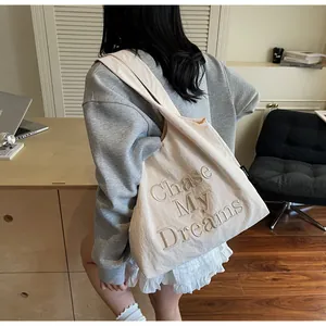 Dettaglio della borsa tote in tela bianco avorio con ricamo 3D e trama del tessuto fine