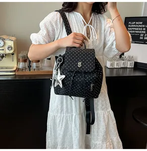 Detailed shot of black star print backpack with silver star pendant in a cafe setting