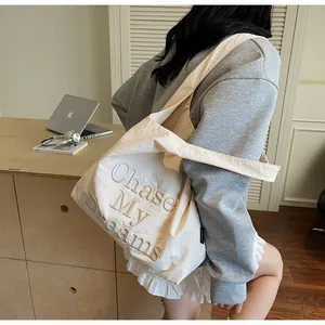Dettaglio della borsa tote in tela crema con ricamo Chase My Dreams e bordo a balze