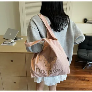 Dettaglio del ricamo su una grande borsa tote rosa con la scritta Chase My Dreams