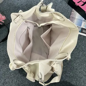 Large beige tote bag with spacious interior compartments and bow detail on the strap