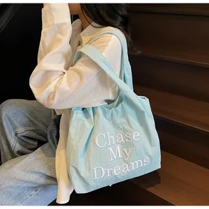 Dettaglio borsa shopper azzurra con ricamo bianco della scritta Chase My Dreams