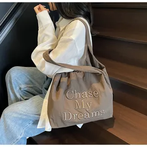 Dettaglio del ricamo Chase My Dreams su una grande borsa tote in tela color caffè