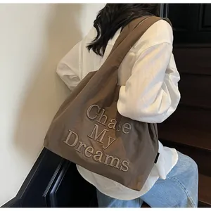 Dettaglio della borsa tote in nylon marrone scuro con ricamo Chase My Dreams decorativo