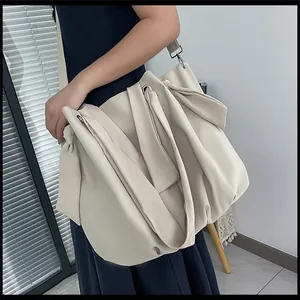 Detail of off-white oversized canvas tote bag with pleated design and metal eyelets