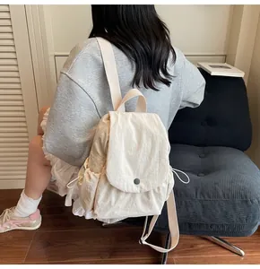 Detail showing high-capacity cream canvas backpack with flap cover and side drawstring pockets