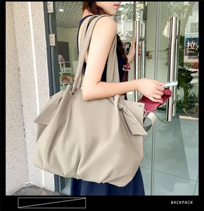 Detailed side view of khaki canvas tote bag featuring decorative ribbon bow and soft texture