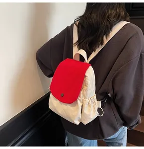 Detail of red and cream waterproof backpack featuring side drawstring pocket and snap button