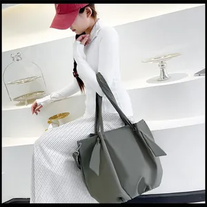 Detailed view of an olive green canvas tote bag with side pleats and adjustable strap
