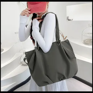 Detail view of a large canvas tote bag with decorative side bow knots on a model