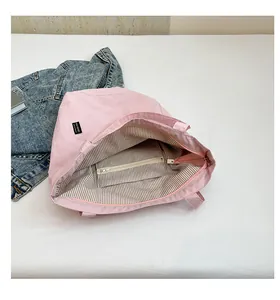 Detail of pink fabric tote bag showing striped lining and internal zipper pocket