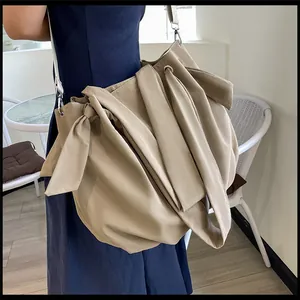 Detail shot of khaki PU tote bag featuring side bows and soft pleated texture