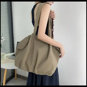Detailed view of the large khaki tote bag showing nylon texture and side pocket design