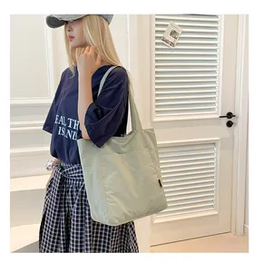 Detail of light green canvas tote bag with large front pocket and shoulder strap