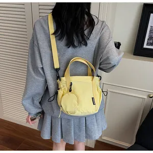 Detail of yellow canvas crossbody bag with round coin purse and adjustable strap