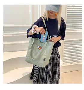 Detail view of a light green nylon tote bag featuring the side label and phone pocket