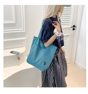 Detail of blue canvas tote bag with a side pocket and black woven label detail
