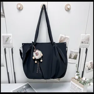 Detail of a large black canvas tote bag featuring a cute white alpaca plush keychain