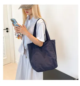 Detail shot of navy blue nylon tote bag showing lightweight fabric and durable side label