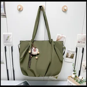 Detail of army green nylon tote bag with knot decor and white sheep plush charm