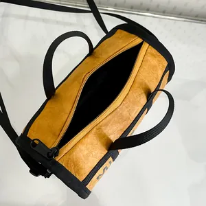 Yellow cylinder duffel bag with black straps and crinkle texture for casual travel use