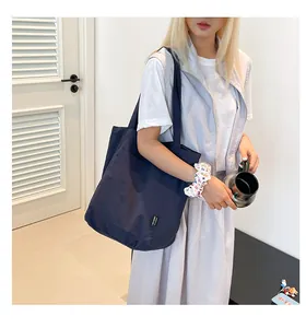Close-up of deep blue nylon tote bag featuring 'YES HONEY' patch and durable handles