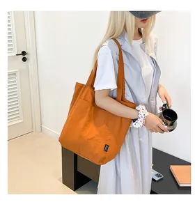 Close-up of vibrant orange nylon tote bag with black Yes Honey side woven label