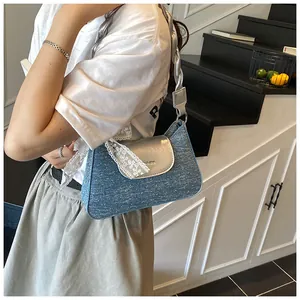 Detail of blue denim shoulder bag with white lace trim and metallic silver strap