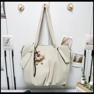 Detail of a beige canvas tote bag with a soft knot design and a cute sheep plush charm