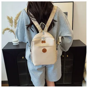 Detail of beige nylon mini backpack with leather logo patch and brown zipper pullers