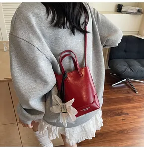 Close-up of red leather bucket bag featuring a white flower charm and side text detail