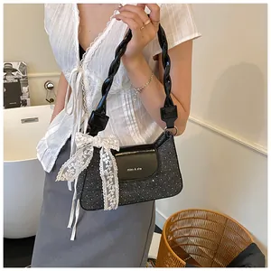 Detail of black sequined underarm bag with twisted handle and white lace bow decoration