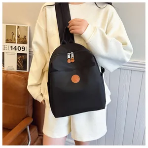 Detail of black nylon backpack with metal zippers and leather pullers held by a model