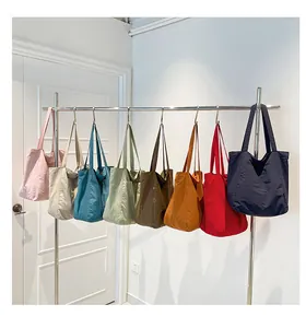 Row of colorful minimalist tote bags hanging on a metal rack showing variety of 8 colors
