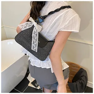 Detail of dark grey textured underarm bag with lace bow and woven shoulder strap