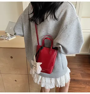Detail of red leather bucket bag with floral charm and delicate brand lettering