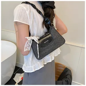 Detail of black textured shoulder bag featuring white lace bow and woven rope strap