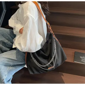 Detail of nylon tote with silver chains and brown leather strap on wooden stairs