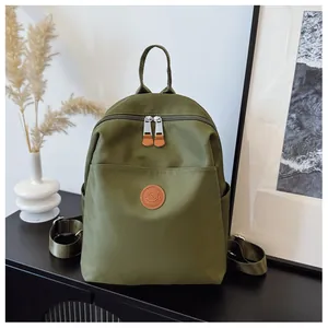 Detailed macro view of the army green nylon backpack with brown leather logo and zipper