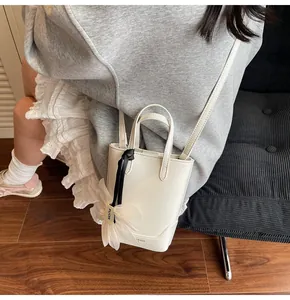 Detail of off-white mini bucket bag with mesh flower charm and black ribbon strap
