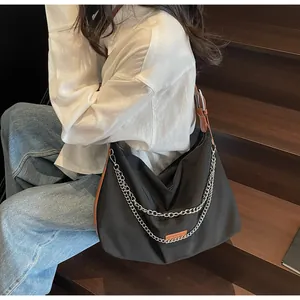 Detail of black large nylon hobo bag featuring silver chains and leather trim detail