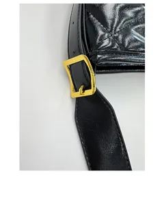Detailed close-up of glossy quilted black leather shoulder bag with gold metal buckle
