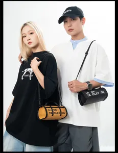 Detail of tan and black cylinder bags with letter prints and adjustable shoulder straps