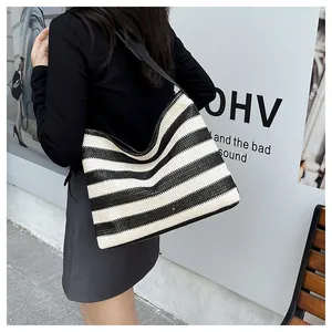Détail du sac cabas en paille tissée à rayures avec bandoulières noires en extérieur