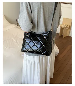 Detail of black quilted shoulder bag with gold rivets and 'FASHION' tag accessory