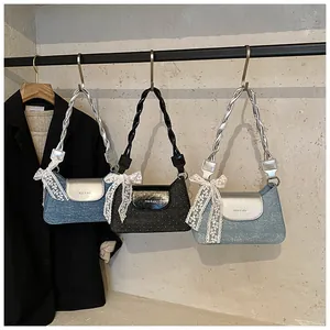 Three stylish underarm bags in denim and shimmer fabrics with lace bows and woven straps