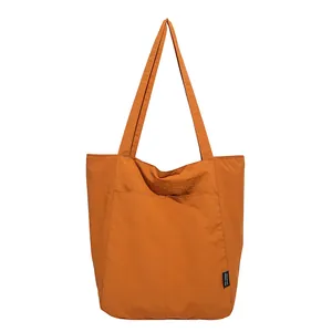Minimalist ginger yellow nylon tote bag with large front pocket on white background