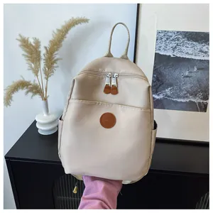 Detail view of stylish beige nylon backpack with leather logo and waterproof material