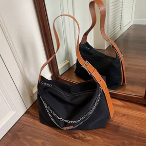 Black nylon shoulder bag with adjustable brown leather strap and silver chain detail